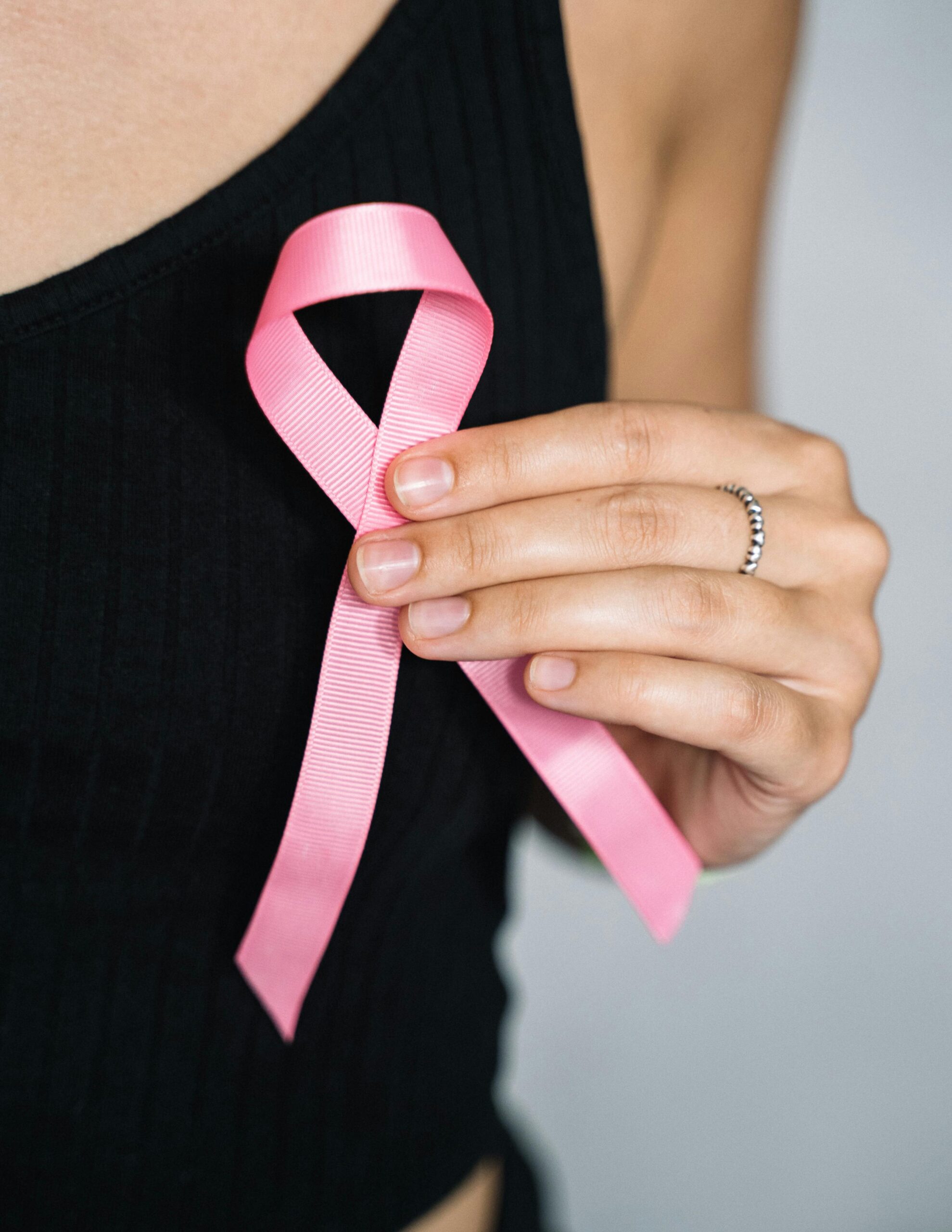 close up of woman holding a pink ribbon