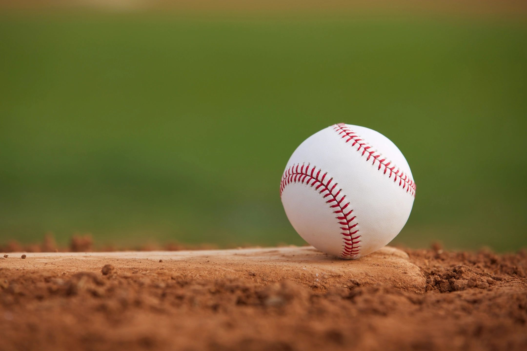 A closeup of a baseball sitting in the dirt